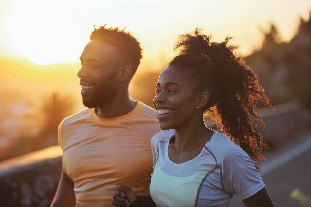 Fit young couple smiling while out for a run together along the road at sunset adult togetherness friendship.