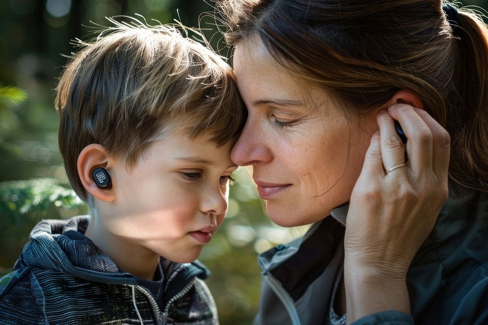 Mother helping her son with his Hearing Aid on his ear portrait adult child.