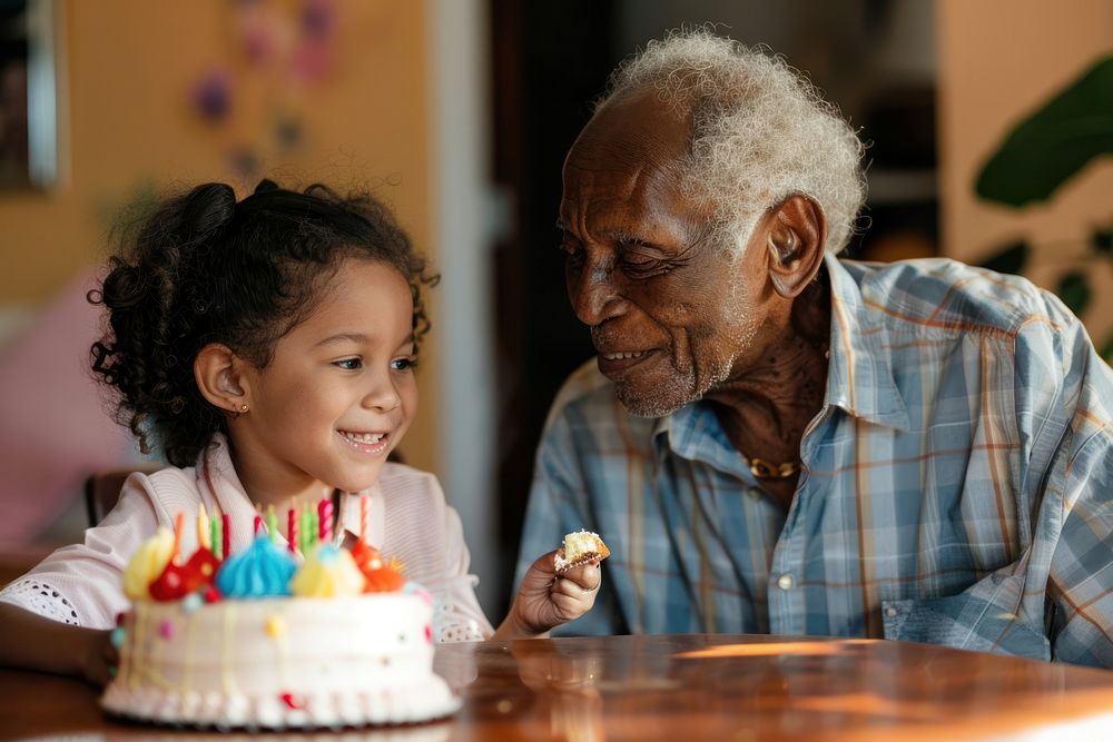 African Grandfather watching Hispanic girl eating birthday cake dessert people person.