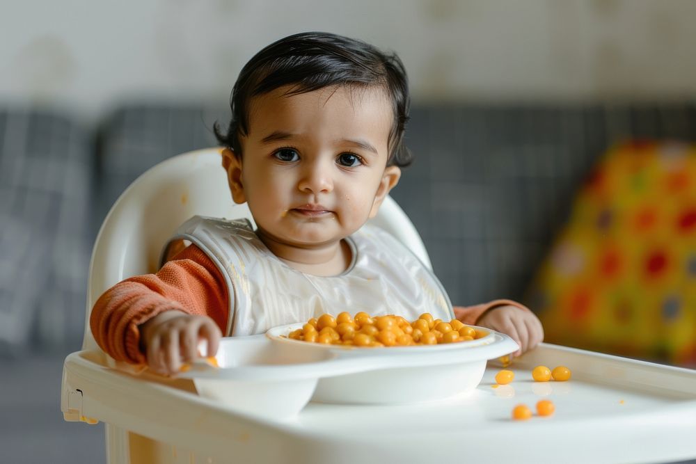 Indian toddler sitting in a high chair photo bowl food.