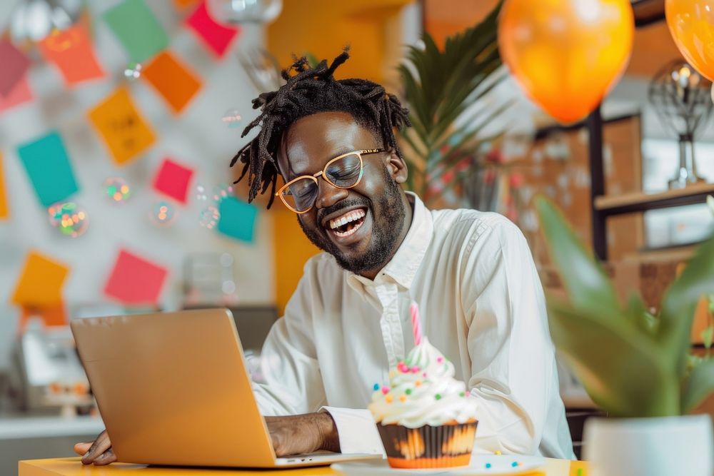 Laughing African businessman celebrating his birthday laughing laptop cake.
