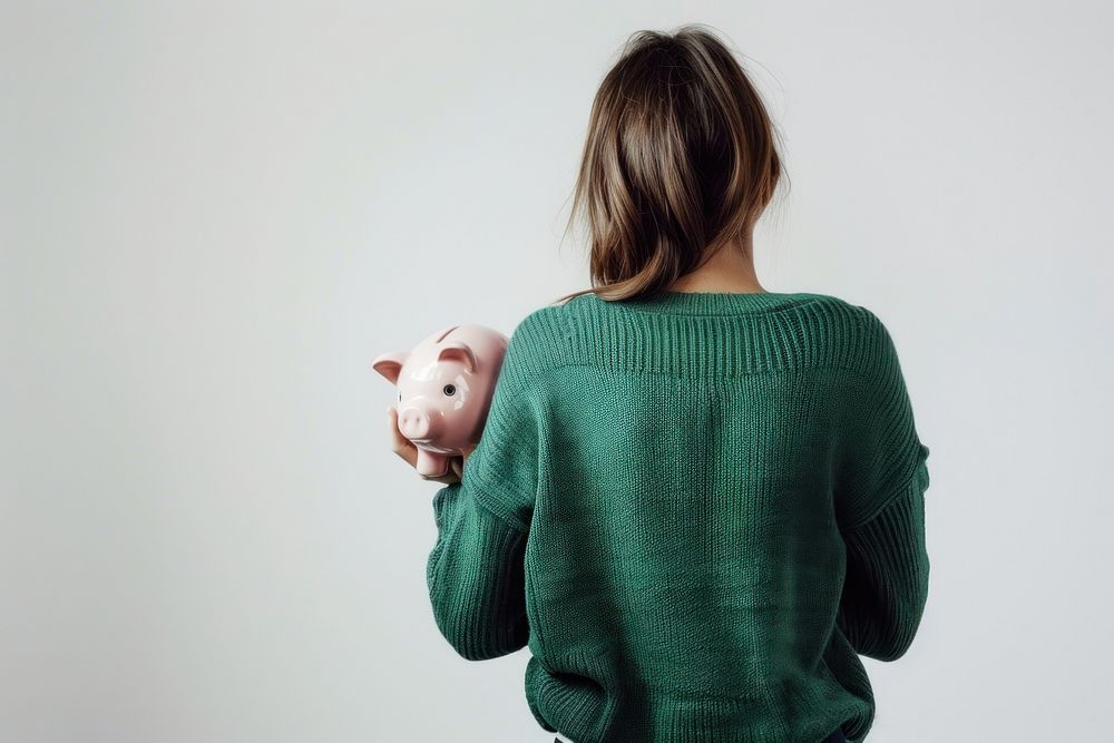 Girl hold piggy bank sweater clothing knitwear.