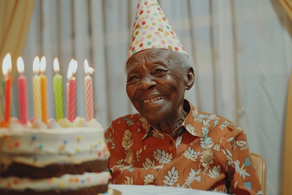 Happy lovely elderly African wearing party hat cake birthday cake dessert.