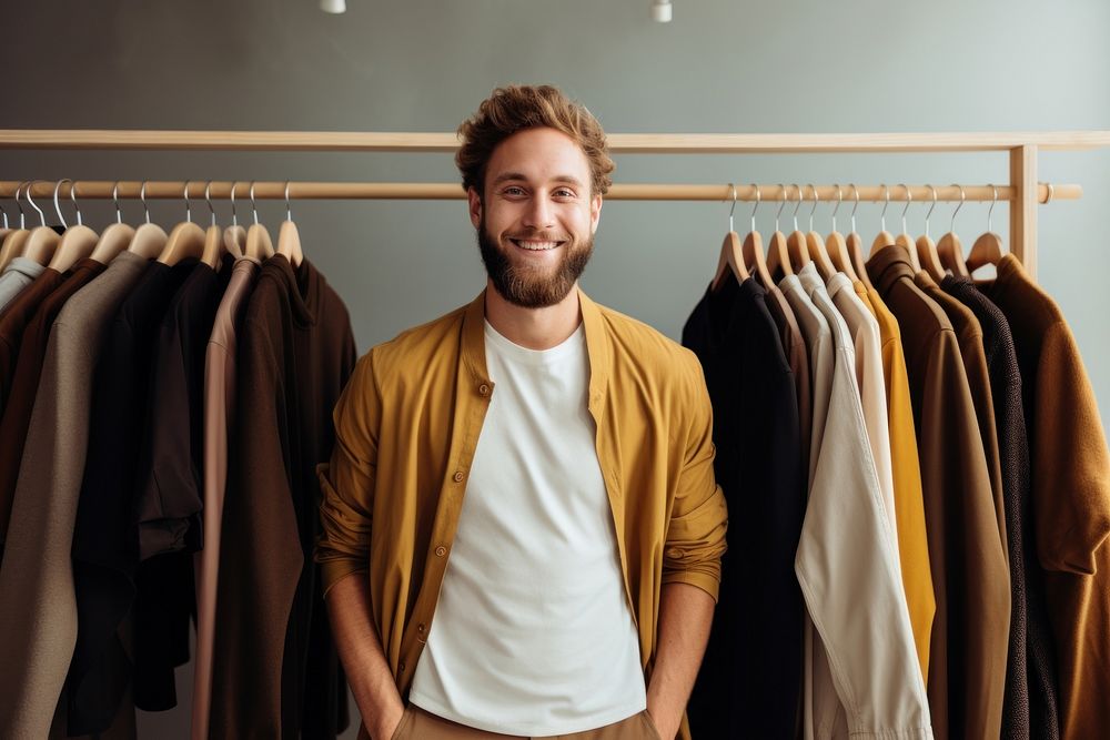 Smiling male standing near hangers with brand wear furniture indoors person.