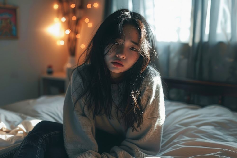 Asian girl looking tired sitting on bed portrait worried adult.