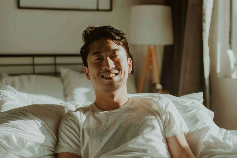 Asian men looking happy sitting on bed furniture smile adult.