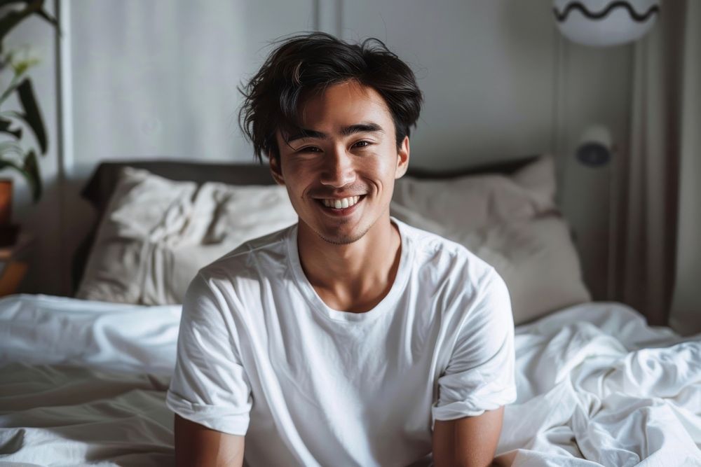 Asian men looking happy sitting on bed furniture smile relaxation.