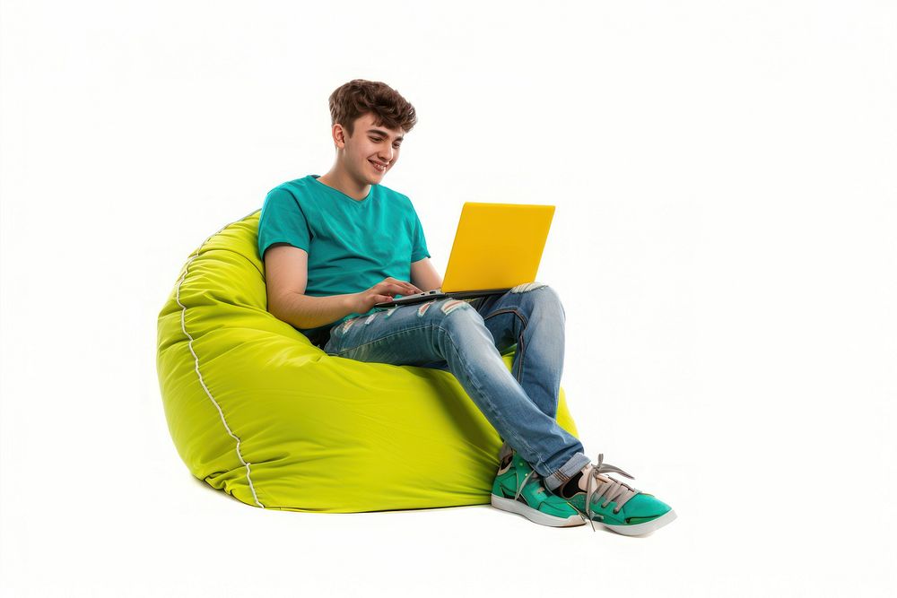 Cheerful man working on laptop seated on a minimal luxury color beanbag furniture computer white background.