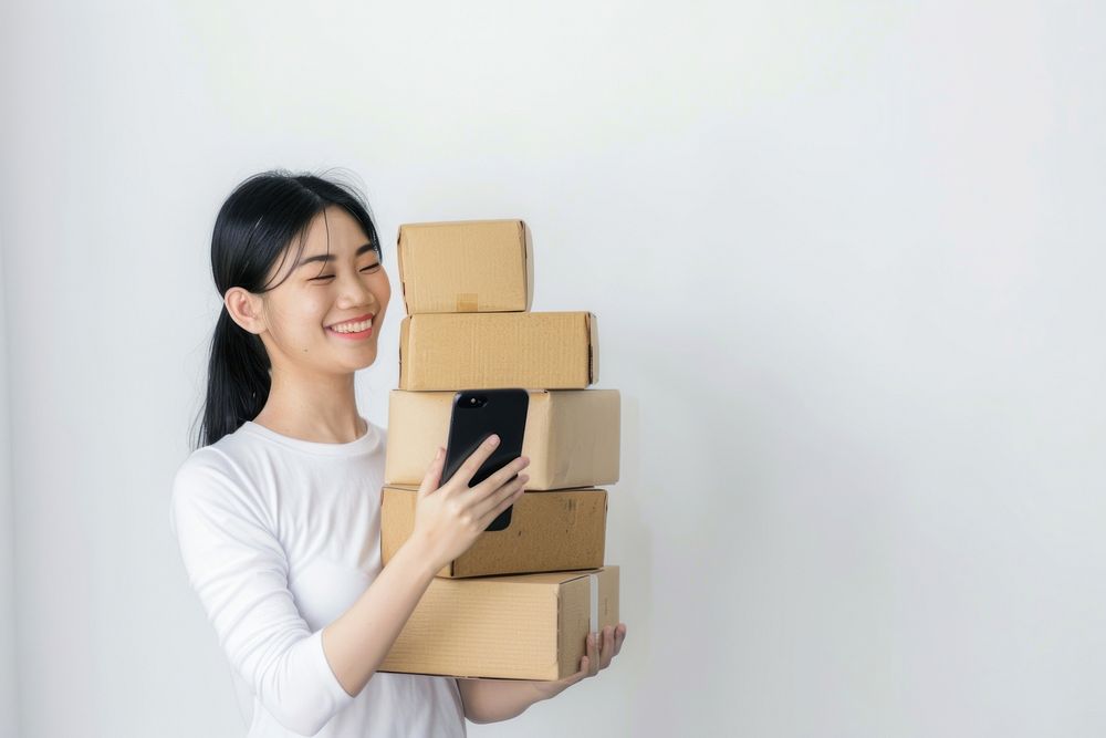 Happy woman holding stack box cardboard phone mobile phone.