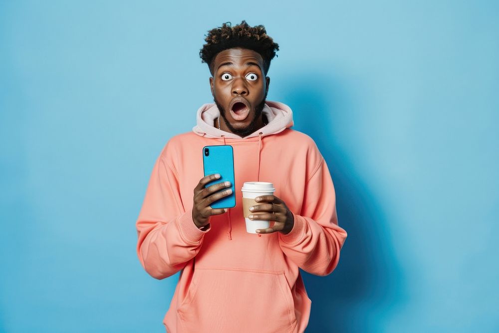 Black man holding phone and coffee cup sweatshirt surprised clothing.