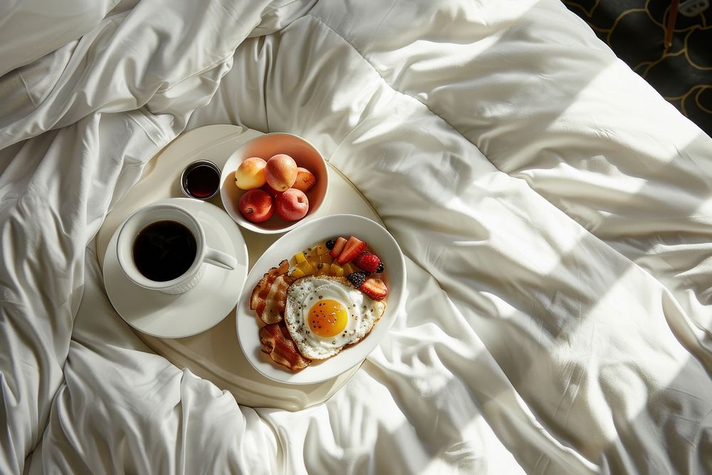 A luxury hotel bed with a breakfast tray coffee food egg.