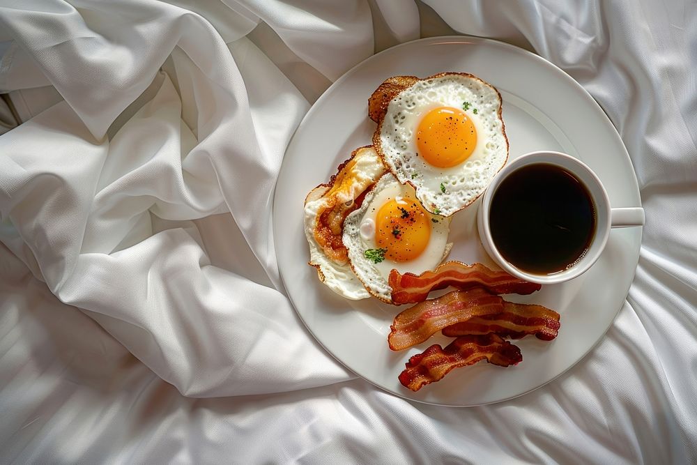 A luxury hotel bed with a breakfast tray food egg brunch.