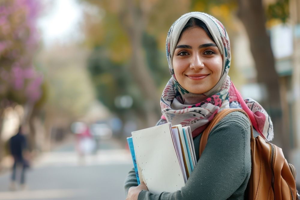 Young Iranian Female Student Standing Outdoors With Workbooks In Hands clothing dimples apparel.