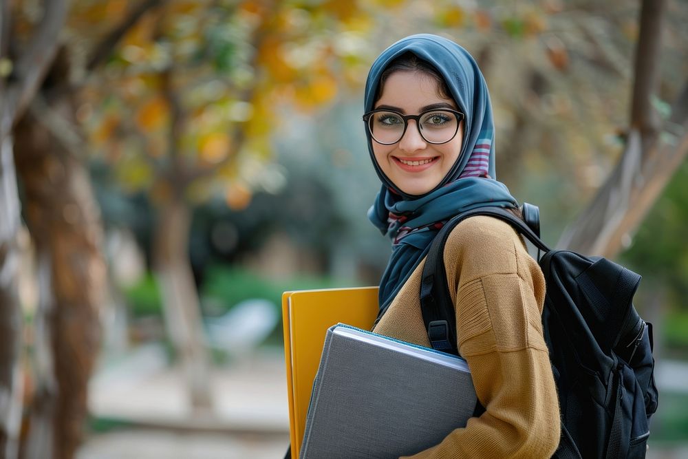 Young Iranian Female Student Standing Outdoors With Workbooks In Hands female clothing apparel.