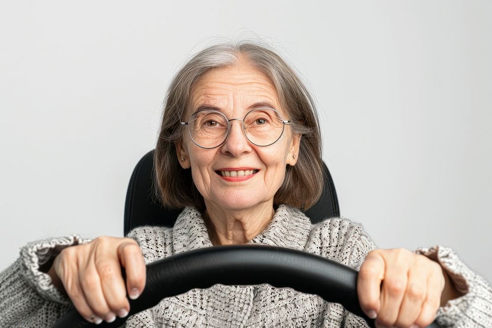 Elder woman holding a car steering wheel portrait glasses vehicle.