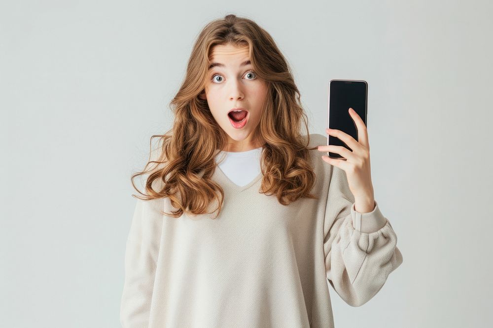 Shock young woman holding phone white background.