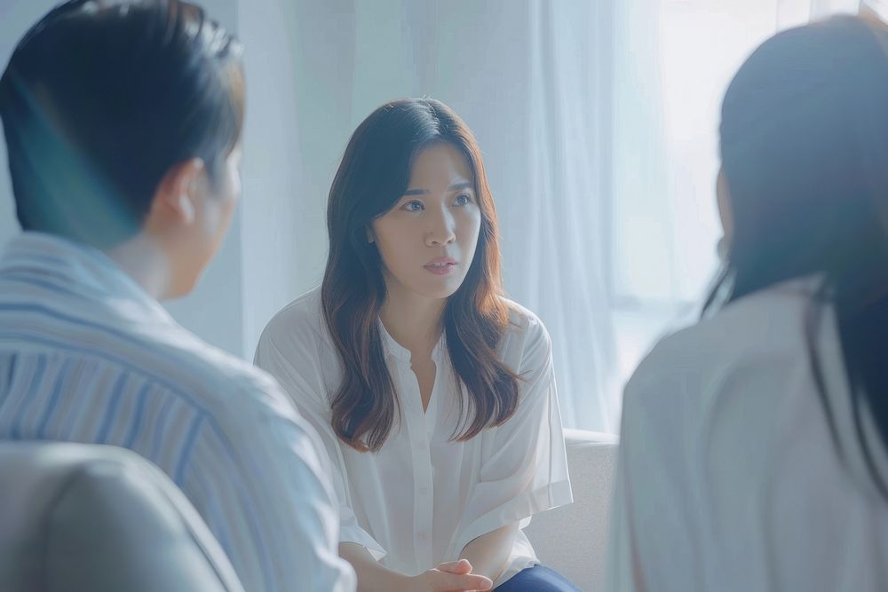 An asian psychologist sit opposite to a couple and listen to them conversation person female.