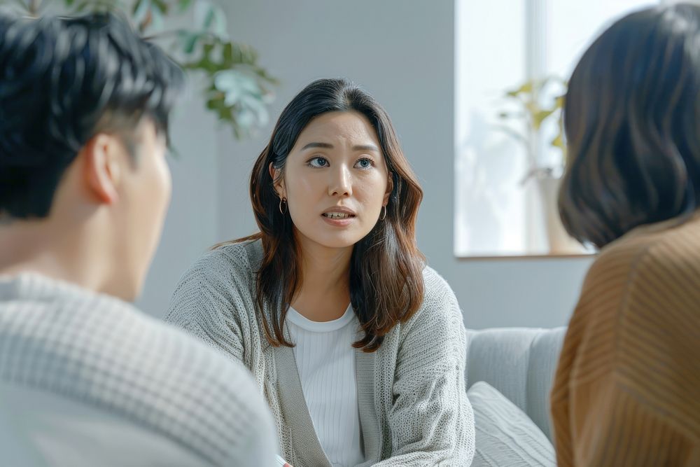 An asian psychologist sit opposite to a couple conversation person female.