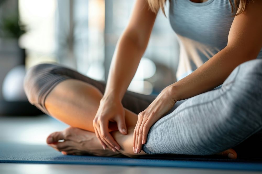 Yoga teacher move leg of a yoga student exercise fitness female.