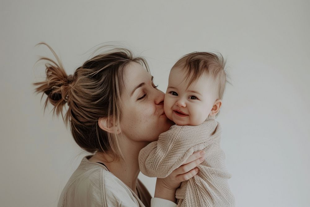 Happy mother kissing on cheek baby portrait adult photo.