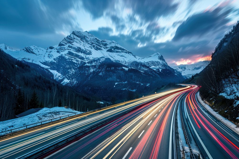Cars speed light trails on a highway in the alps mountain outdoors nature.