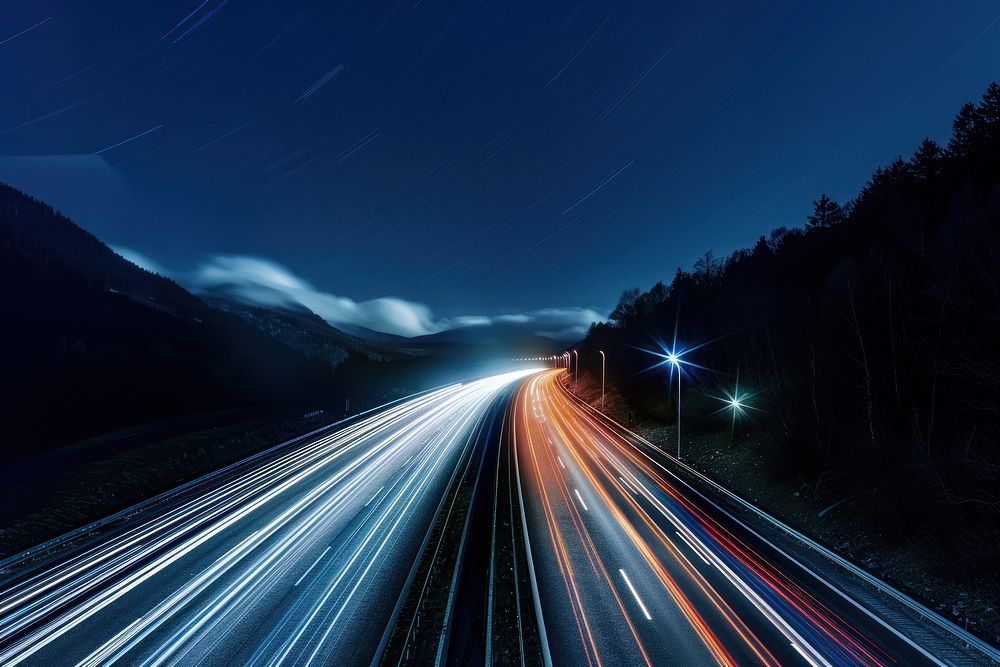 Cars speed light trails on a highway in the alps sky outdoors nature.
