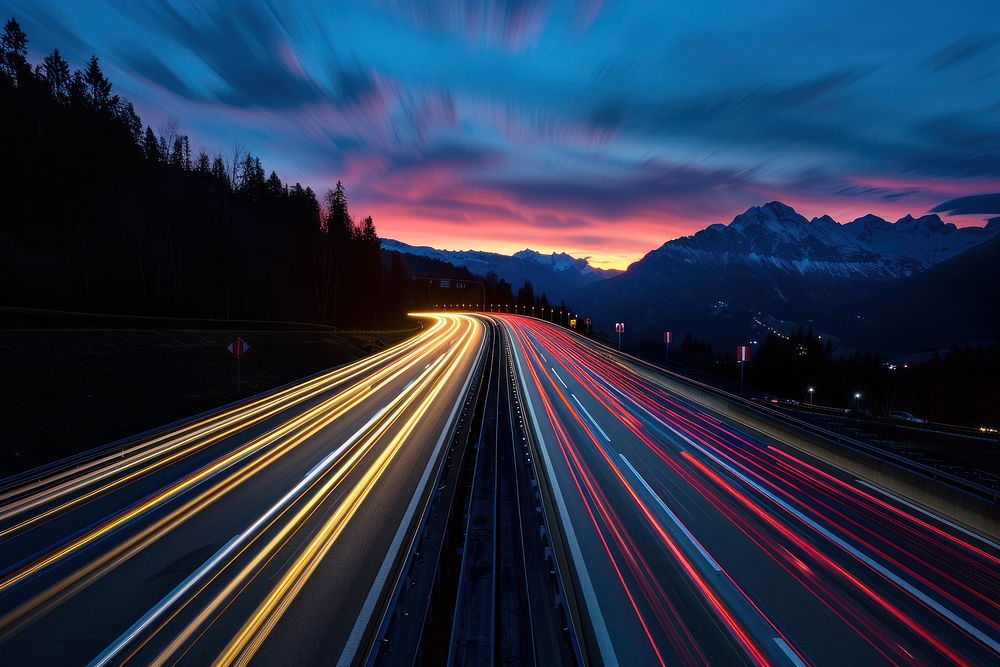 Cars speed lights on a highway in the alp mountains sky outdoors evening.