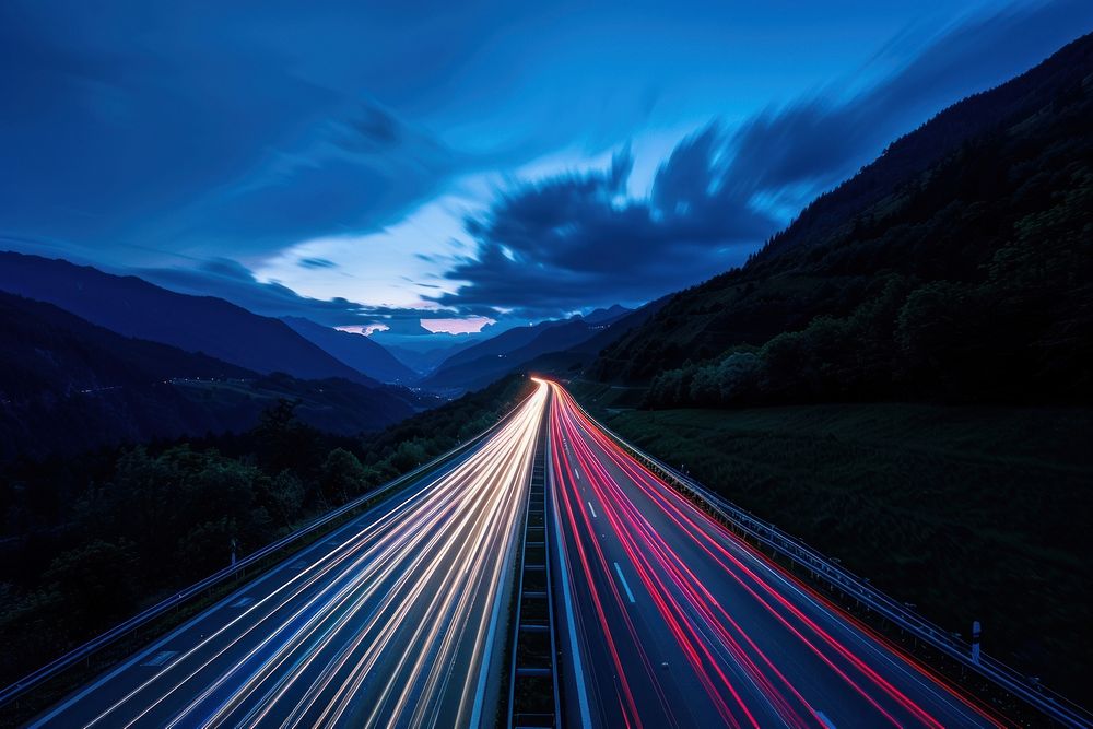 Cars speed lights on a highway in the alp mountains sky outdoors nature.
