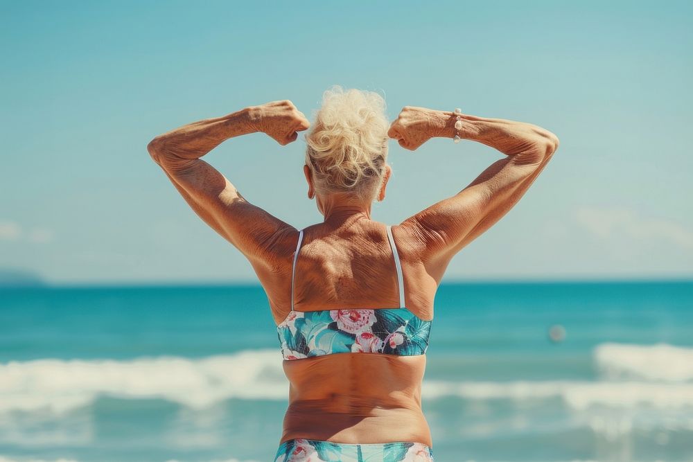 Senior woman in back flexing her muscles blonde person female.