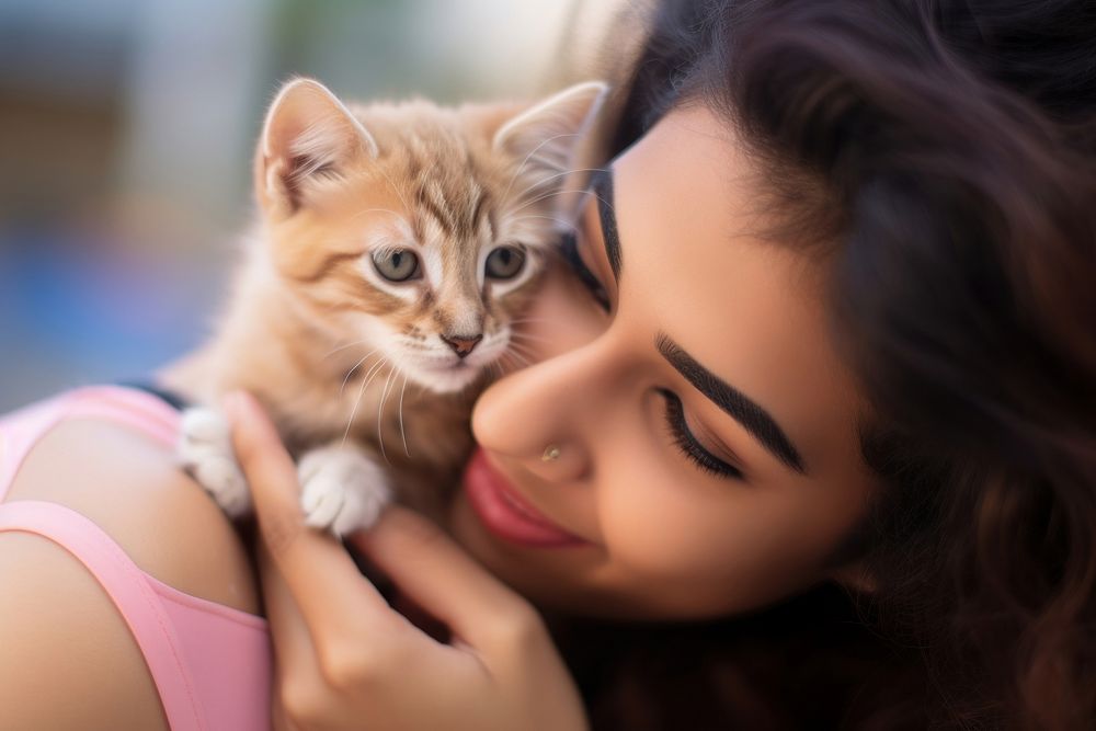 Latinx young woman playing with a kitty animal mammal kitten.