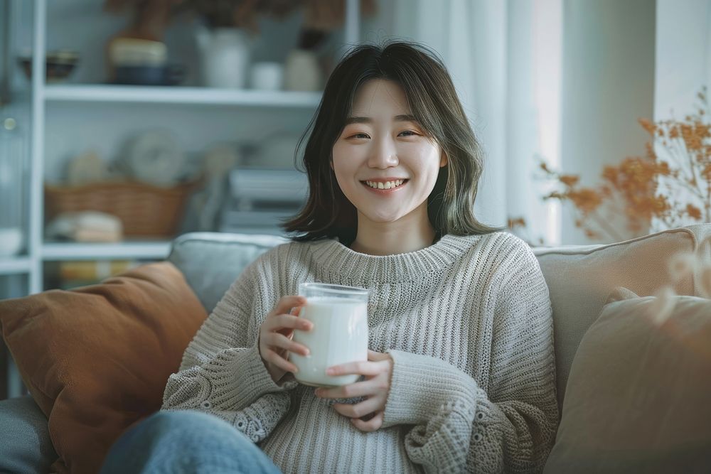 Pregnant korean woman drinking smiling sitting.