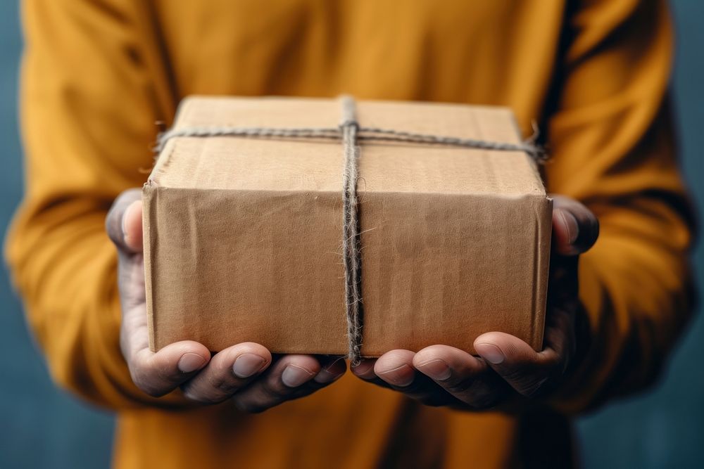 Closeup hands of delivery man holding package to deliver box cardboard celebration.
