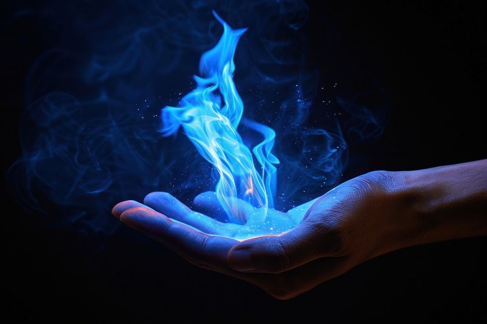 Hand fire flame smoke blue black background.