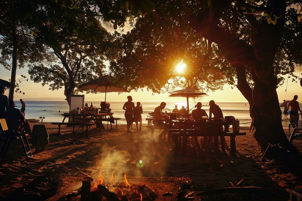 People party with BBQ grilling meat beach waterfront shoreline.