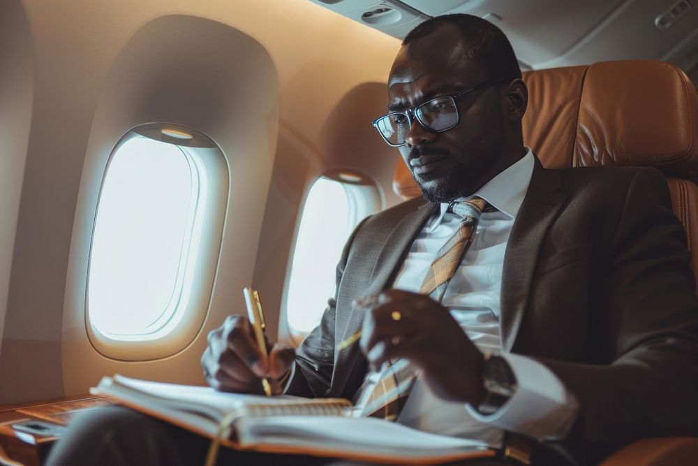 African businessman sitting on an airplane seat and writing vehicle glasses adult.