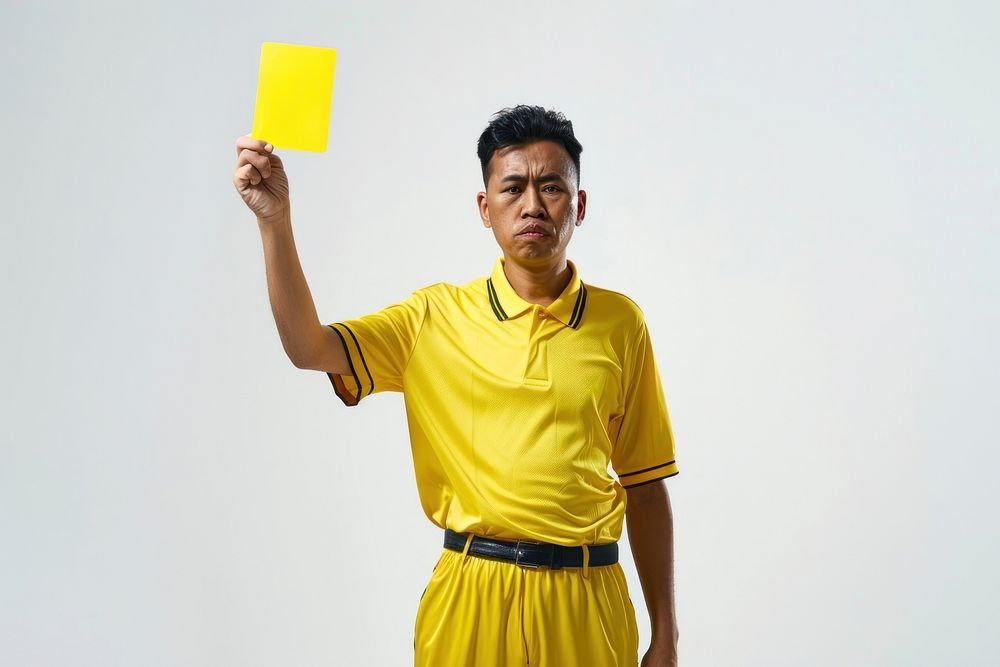 Photo of a referee showing a yellow card while holding it upwards adult white background triumphant.