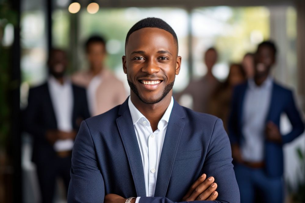 Smiling confident african businessman looking at camera and standing in an office at team meeting smiling adult smile.
