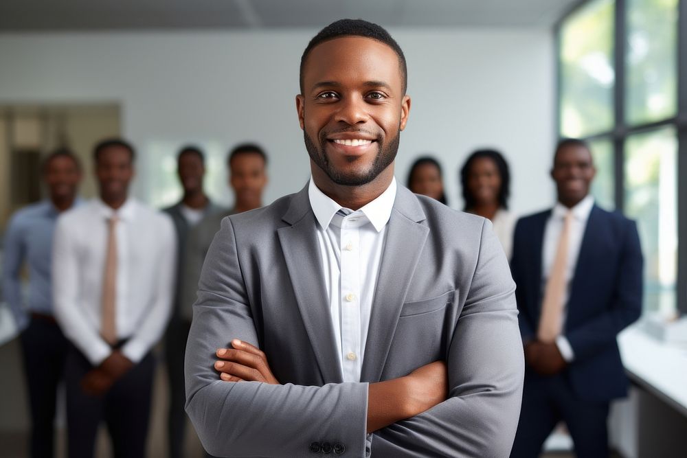 Smiling confident african businessman looking at camera and standing in an office at team meeting smiling adult accessories.