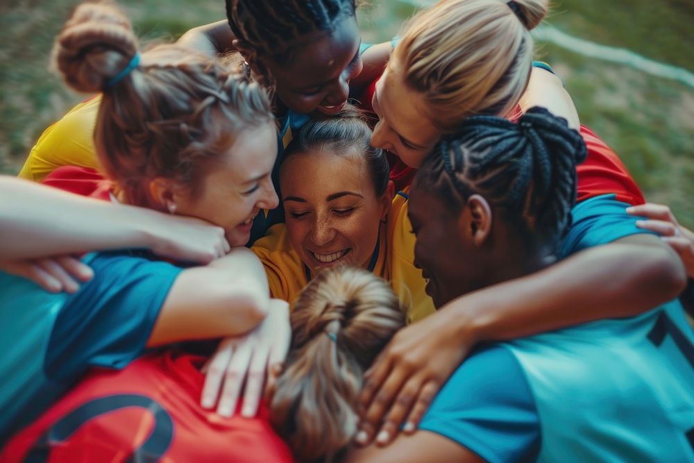Multi-ethnic female soccer huddle hugging people.