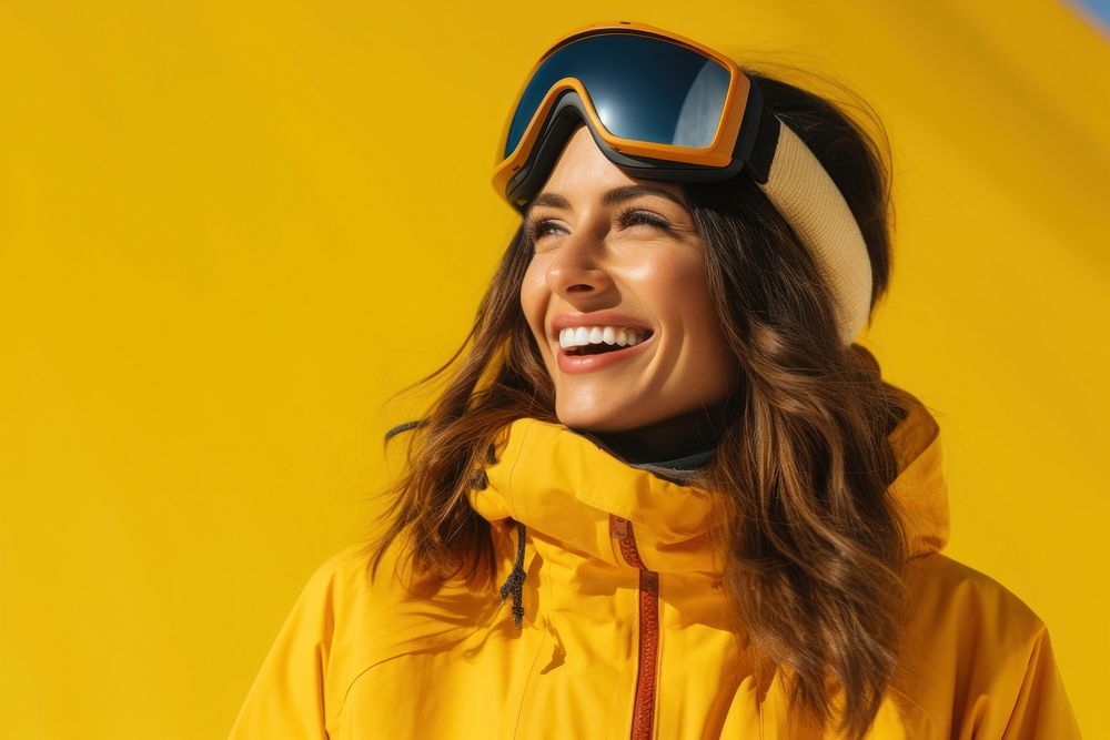 Woman holding ski goggles laughing portrait yellow.