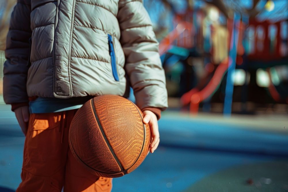 Kid holding baskateball playground basketball outdoors.