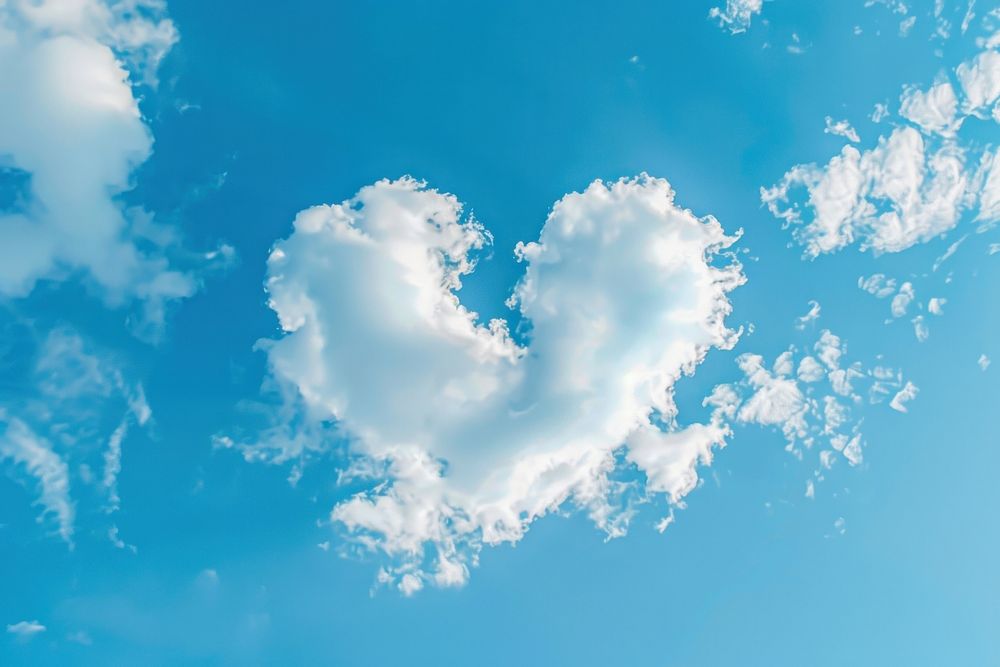 Heart shaped as a clouds in the blue sky background outdoors nature symbol.