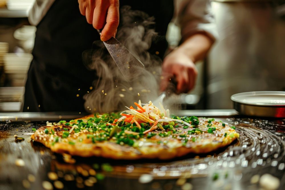 Chef cooking okonomiyaki at Japanese restaurant sprinkling weaponry wedding.
