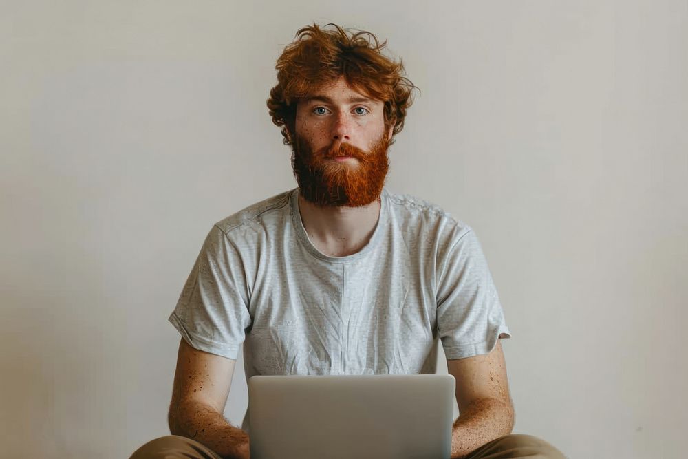 Full body young redhead bearded man in t-shirt casual clothes sitting hold use work on laptop point aside electronics…