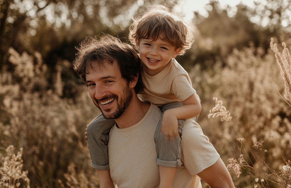 Father carrying his son happy smiling outdoor.