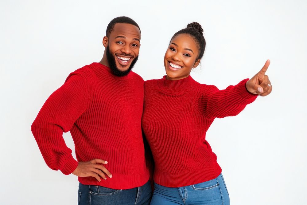 Couple in red sweaters and jeans pointing to the right happy smiling face.