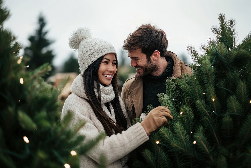 A couple buy a big fresh christmas tree at pine tree farm together clothing smiling lights.