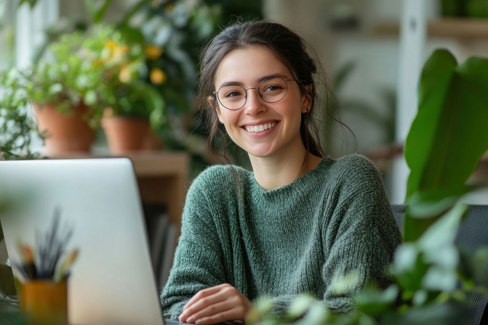 Smile female employee sweater glasses laptop.