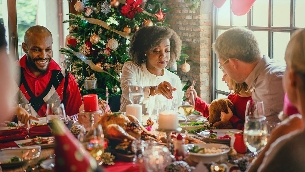 Festive family dinner with diverse group. Christmas tree, holiday meal, and decorations. Joyful gathering, festive…