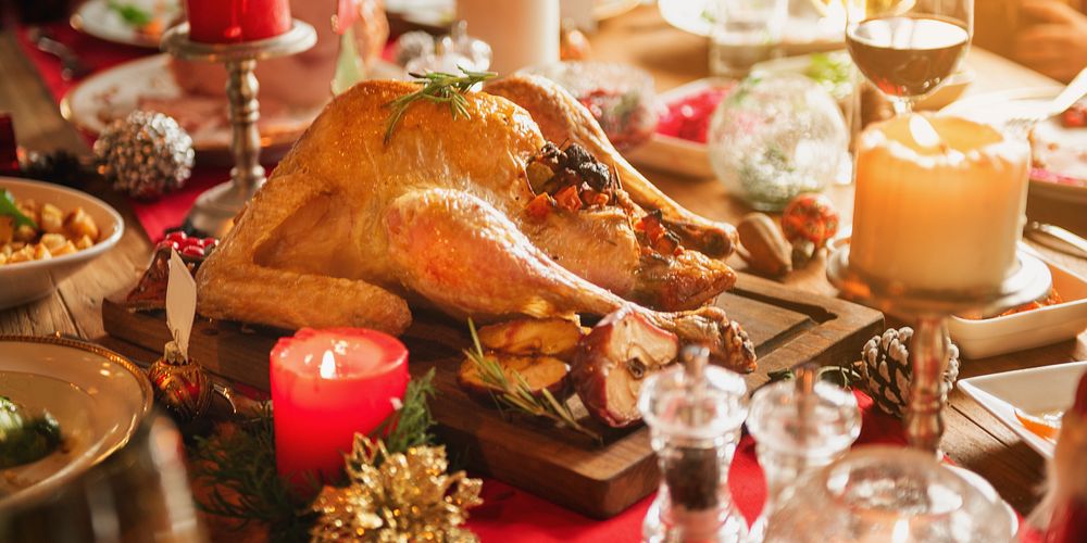 Festive holiday dinner with a roasted turkey centerpiece. Candles and decorations create a warm, inviting atmosphere.…